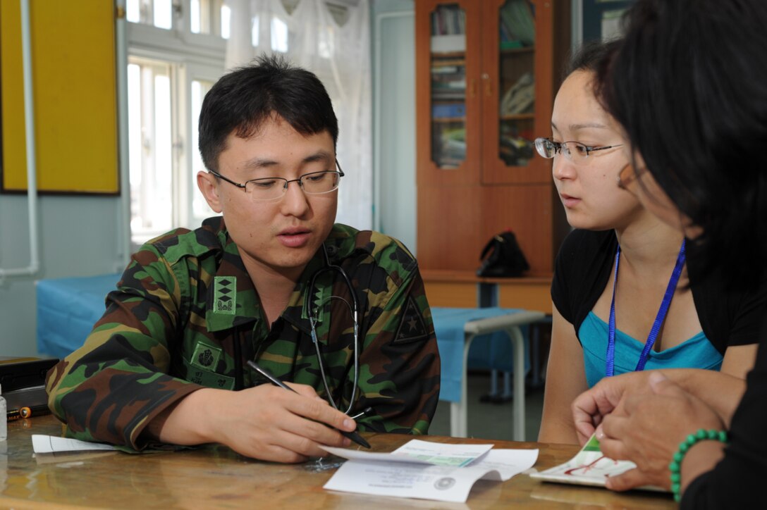 English and Mongolian translator, Miss Uyanga Ganbat watches as Capt. MinYoung Kim, a doctor with the Republic of Korea, writes down a few healthcare suggestions for a Mongolian woman during a check-up at the temporary clinic held in the Buynt Uhaa Complex in Ulaanbaatar, Mongolia on Aug. 7 during Khaan Quest 2011, a combined joint-exercise hosted by the Mongolian Armed Forces in partnership with U.S. Pacific Command forces.  Khaan Quest is in its eighth year and has military participants from Canada, India, the Republic of Korea, the United States, Mongolia and others. In addition to a medical civic action event, there is an engineering outreach event, a Command Post exercise and several field exercises. Khaan Quest officially started July 31 and continues until Aug 12.